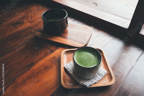 Two cups of hot matcha latte on wooden floor