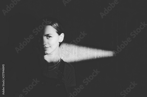 Black and white shot of woman from darkness with light ray on her face photo