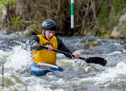 A canoeist paddling through fast running white water - about to go down a drop