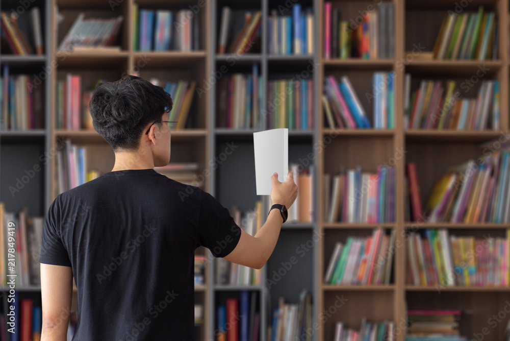 Man picking up book from shelf Man picking up book from shelf