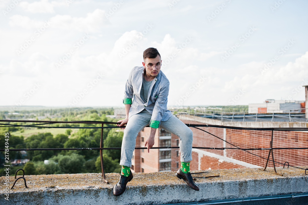 Dreamer stylish macho man in gray suit and glasses posed on the roof. Dreamer stylish macho man in gray suit and glasses posed on the roof.