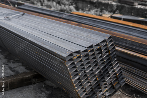 Square flat-rolled pipe metal profile in packs at the warehouse of metal products. Weathered metals profiles for construction. Metal corrosion. photo