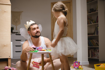 Little daughter and father have fun, dressing in princess costume, daddy makeup