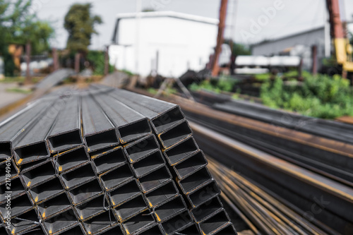 Square flat-rolled pipe metal profile in packs at the warehouse of metal products. Weathered metals profiles for construction. Metal corrosion. photo