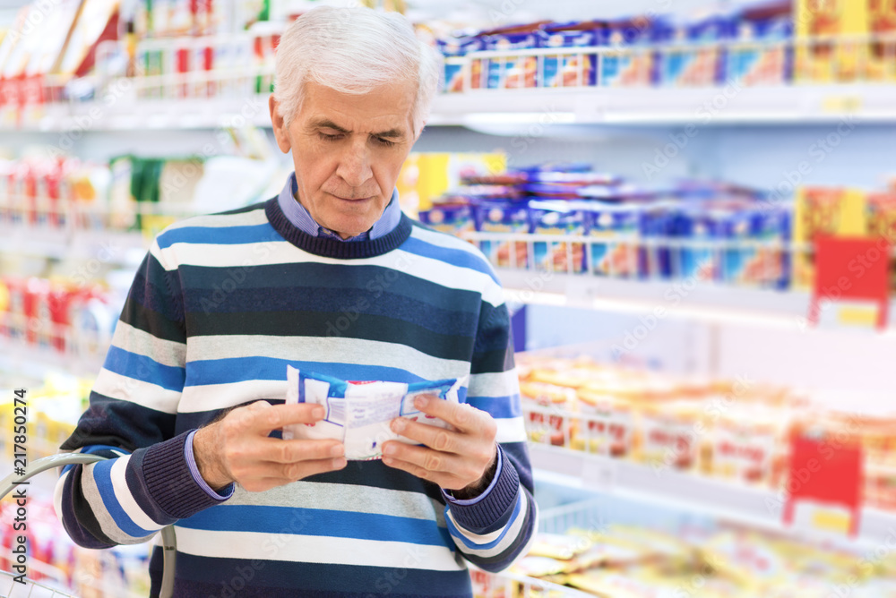 Senior man reading food label at a grocery store Senior man reading food label at a grocery store
