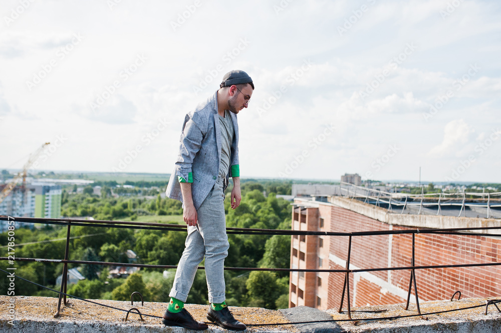 Dreamer stylish macho man in gray suit, hat and glasses posed on the roof. Dreamer stylish macho man in gray suit, hat and glasses posed on the roof.
