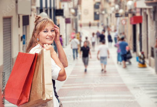 Happy girl walks through the street after shopping. She holding bugs. Closeup portrait with free space for text. Shopping in Europe. Shopping Route.