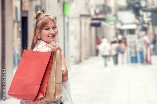 Happy girl walks through the street after shopping. She holding bugs. Closeup portrait with free space for text. Shopping in Europe. Shopping Route.