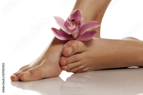 beautifully groomed female feet with orchid on a white background