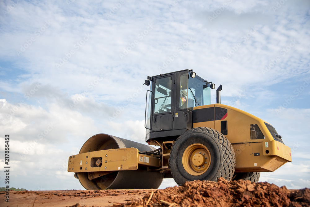 Yellow vibratory soil compactor working on highway construction site Yellow vibratory soil compactor working on highway construction site