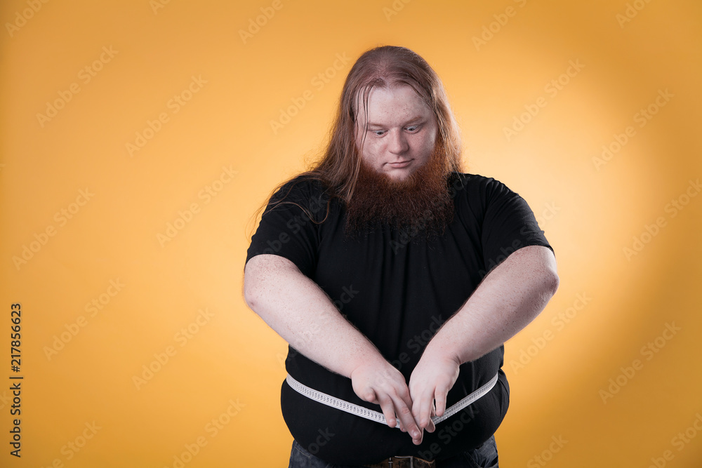 A large fat man measures his large sizes with a ribbon. Stock Photo | Adobe  Stock