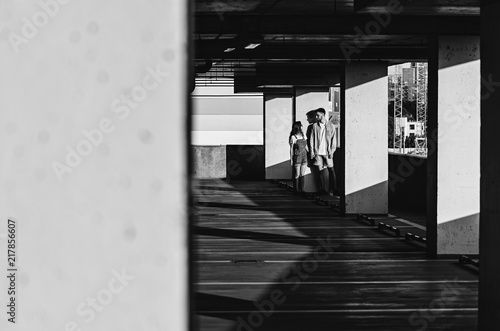 Black and white shot of Couple holding hands and standing near parking wall