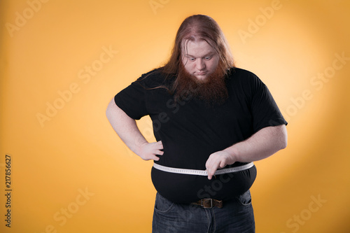 Foto A large fat man measures his large sizes with a ribbon.