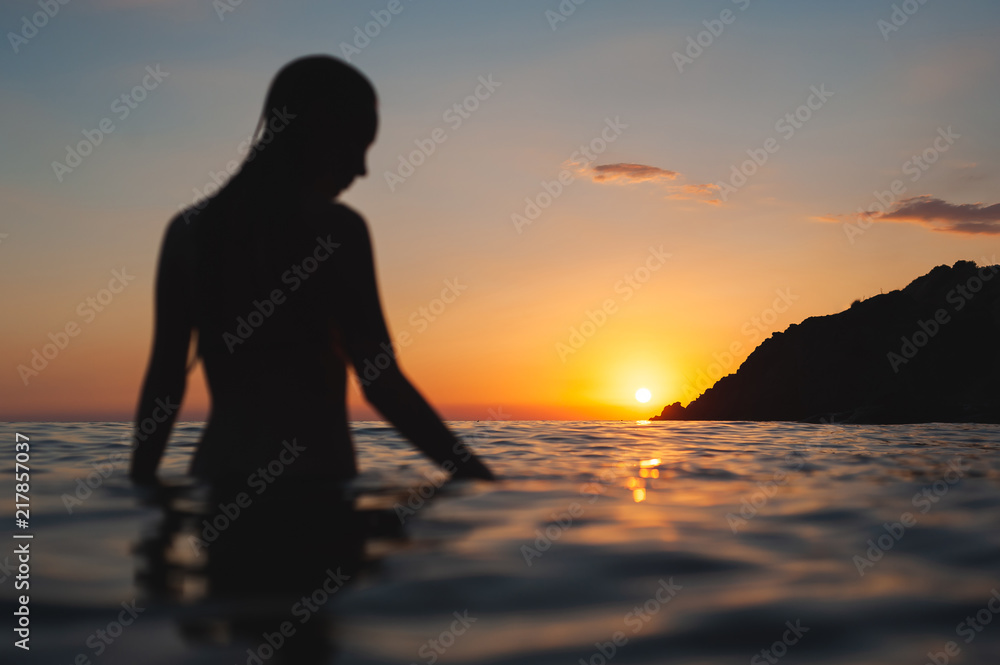 wet woman sunset silhouette in water. Sea bathing at dawn