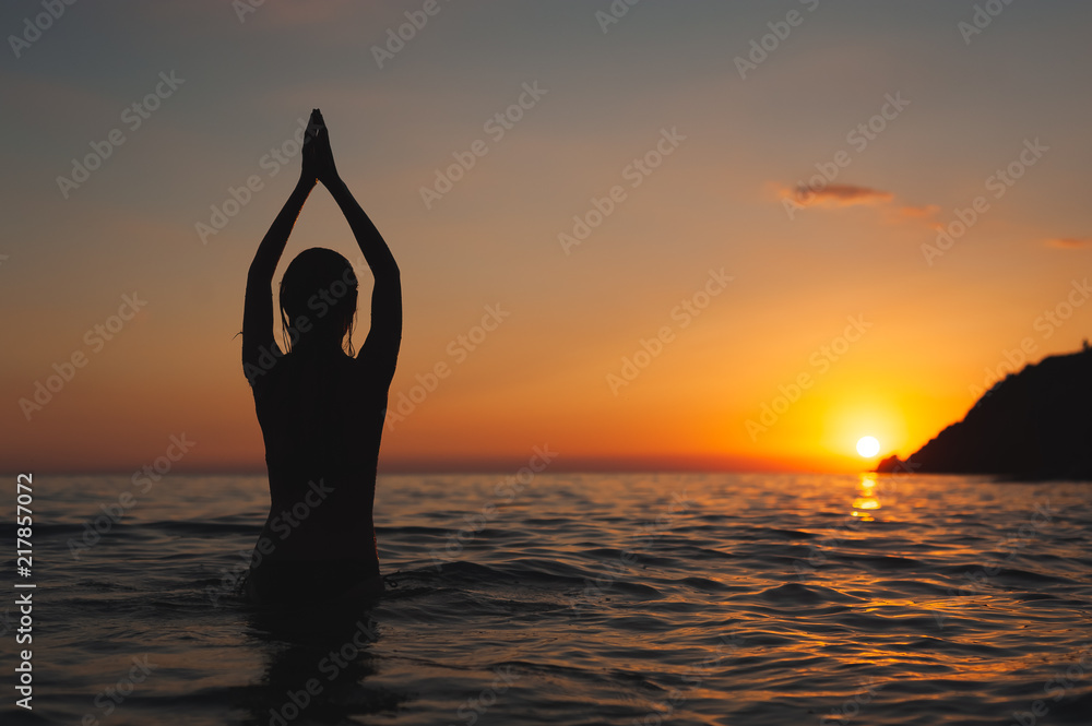 yoga pose woman sunset silhouette in sea. Ocean bathing at dawn