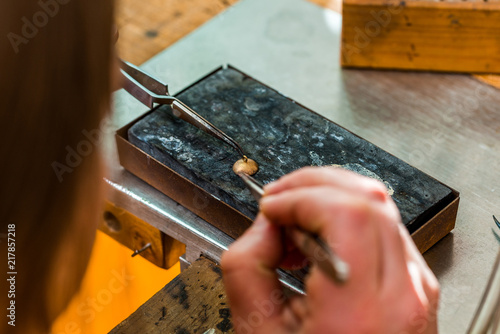 Soldering with a torch flame a jewelry piece at workshop of goldsmith