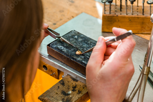 Soldering with a torch flame a jewelry piece at workshop of goldsmith