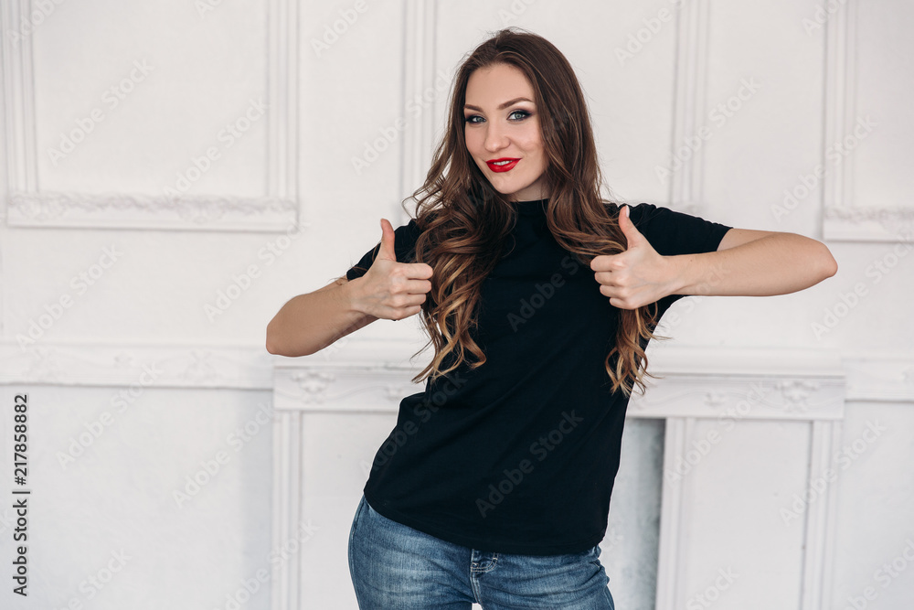 Young girl dressed in casual clothes, has long curled hair, red lips and gray eyes, is surprised by what is happening, shows an emotion of surprise, stands on white background. Young girl dressed in casual clothes, has long curled hair, red lips and gray eyes, is surprised by what is happening, shows an emotion of surprise, stands on white background.