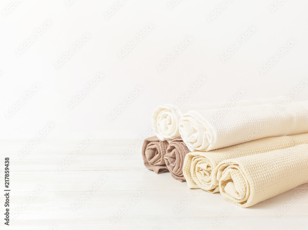 Multicolored clean towels on a light wooden background with copy space. Texture of cotton, waffle towel, textiles. Towels for kitchen or Spa concept. Multicolored clean towels on a light wooden background with copy space. Texture of cotton, waffle towel, textiles. Towels for kitchen or Spa concept.