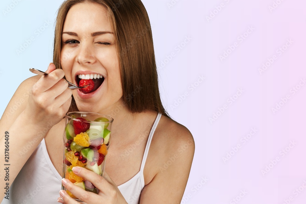 Young woman eating fruits from glass on Young woman eating fruits from glass on