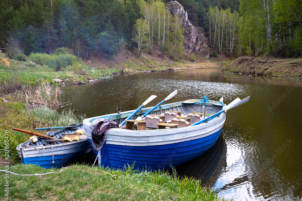 two wooden boats with oars on the bank of the forest river, forest