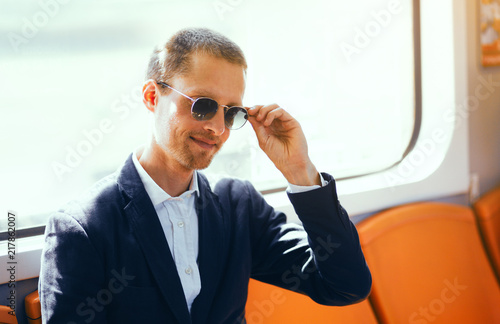 Businessman in sunglasses on subway. Good looking middle aged man wearing shirt and jacket fixing his sunglasses while sitting inside of metro train.