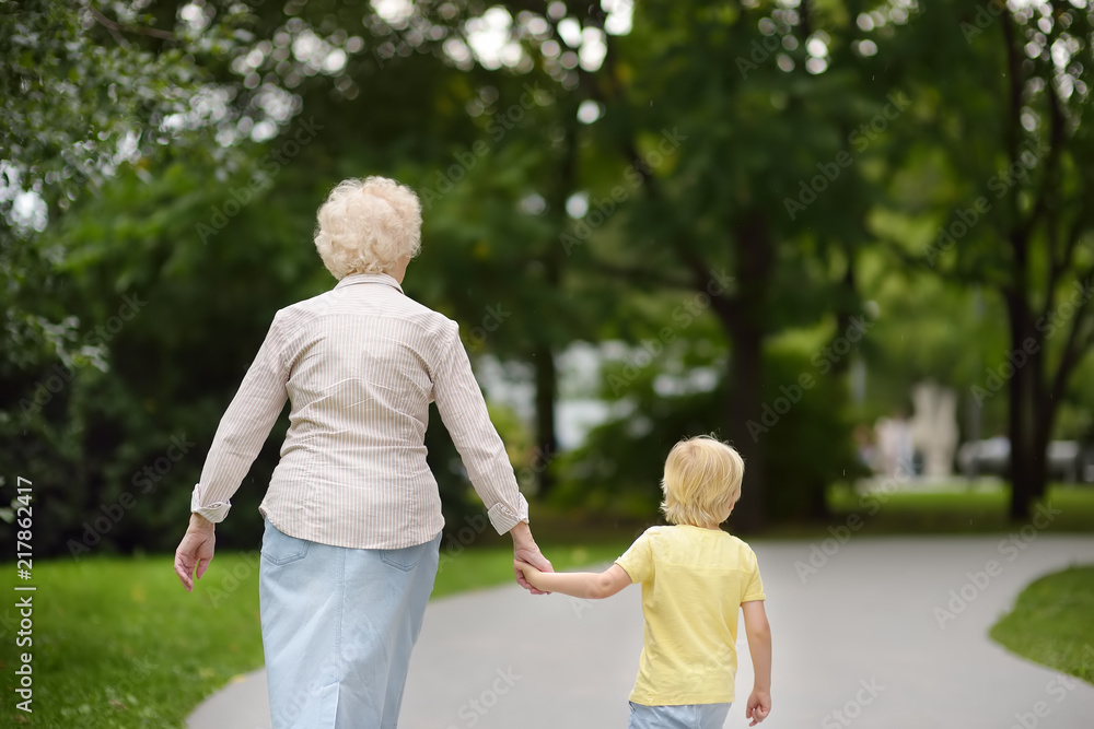 Fototapeta premium Beautiful granny and her little grandson walking together in park