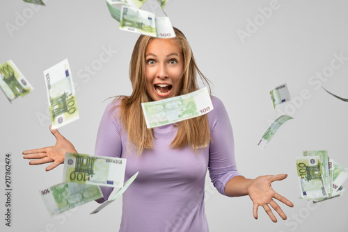 Portrait of cheerful glad girl enjoying shower from 100 euro, flying money, gesturing with hands isolated on gray background