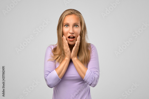 Indoor shot of shocked elegant woman looks with wide eyed expression being horrified to find out that her friend is in hospital, wonders how it happened. Shocking news