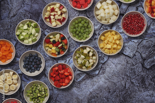 many different bowls with pieces of fruits on a stone surface