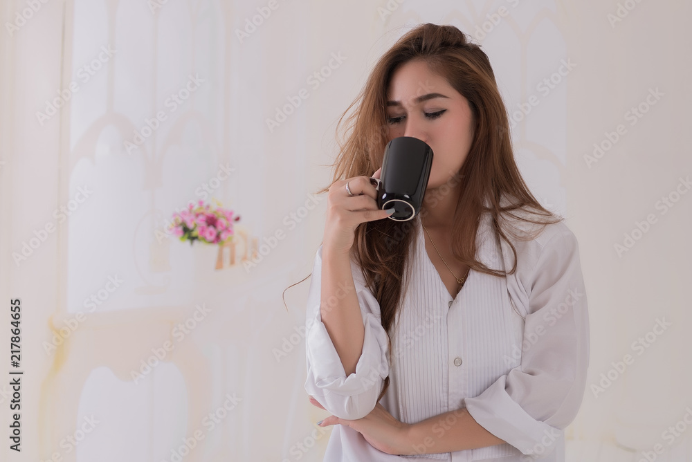 Young asian woman wearing white shirt drink coffee in bed room before work. Thai woman holding coffee cup. Young asian woman wearing white shirt drink coffee in bed room before work. Thai woman holding coffee cup.