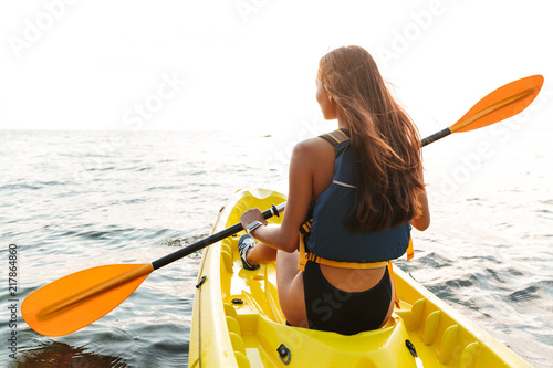 Back view photo of young woman kayaking