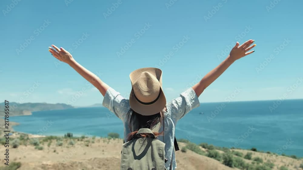 Medium shot active female traveler in sunglasses and hat admiring seascape raising hands Medium shot active female traveler in sunglasses and hat admiring seascape raising hands