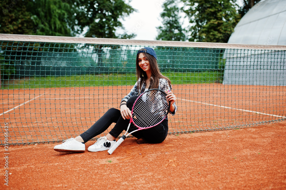 Young sporty girl player with tennis racket on tennis court.