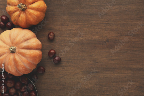 Beautiful pumpkins with leaves and chestnuts on wooden table photo