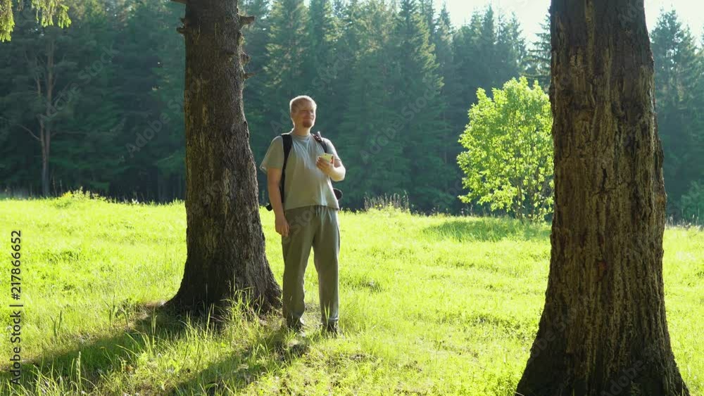 A young lost red-bearded man with a smartphone, looking for direction in the forest. Backpacker watches the gps map signal on the gadget's screen. A young lost red-bearded man with a smartphone, looking for direction in the forest. Backpacker watches the gps map signal on the gadget's screen.