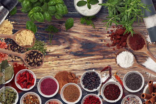 many different spices and herbs on a wooden surface from above photo