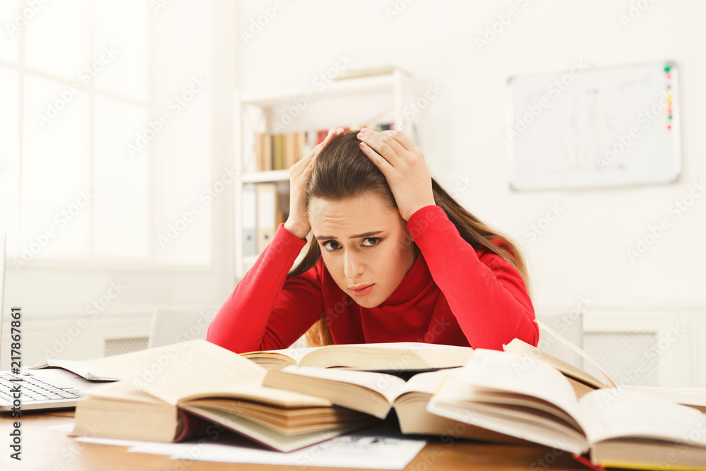 Student girl studying at table full of books Student girl studying at table full of books