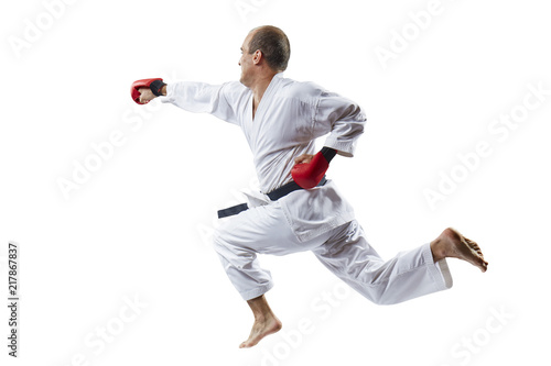 On a white background an athlete with red overlays on his hands beats with a hand in a jump