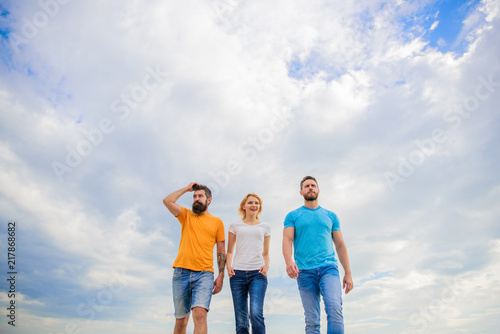 True friendship grow with destiny obstacles. United threesome true friends. Keep moving trough long way. United group purposefully moves forward. Men and woman walks dramatic cloudy sky background
