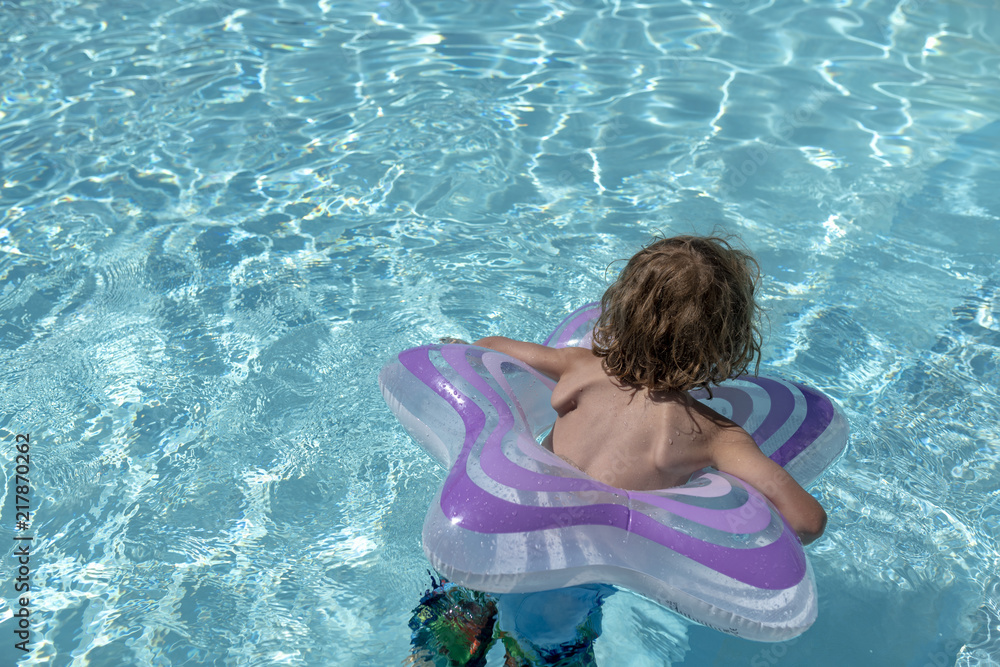 kindergartenkind in einem Lila farbenden Schwimmring in einem Pool