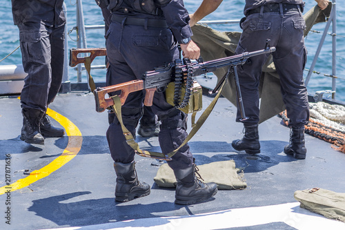 Soldier Shooting with a Machine Gun on a Black Sea Battle / Bulgaria / 07.19.2018 /sailor in black camouflage and shoes is preparing to shoot from the deck of a warship.