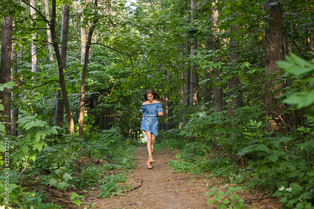Beautiful young woman in dress runing in the summer forest Beautiful young woman in dress runing in the summer forest
