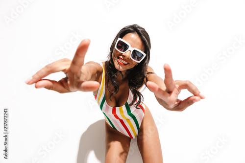 Woman in swimwear posing isolated over white wall background showing peace gesture.