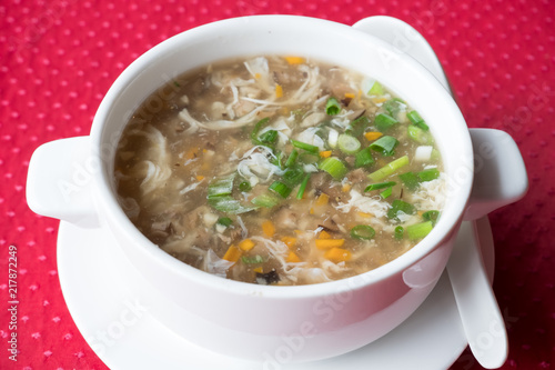 Traditional Chinese soup with beef and vegetables West Lake Beef in a white plate on a red background. Shallow depth of field. photo