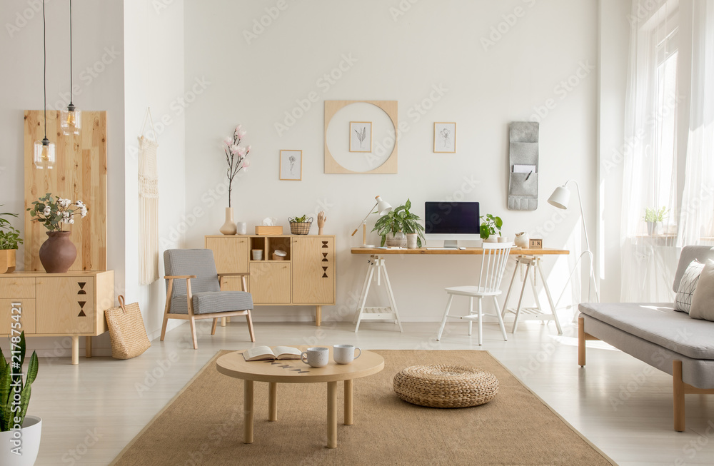 Wooden table and pouf on carpet in white living room interior with poster and workspace. Real photo Wooden table and pouf on carpet in white living room interior with poster and workspace. Real photo