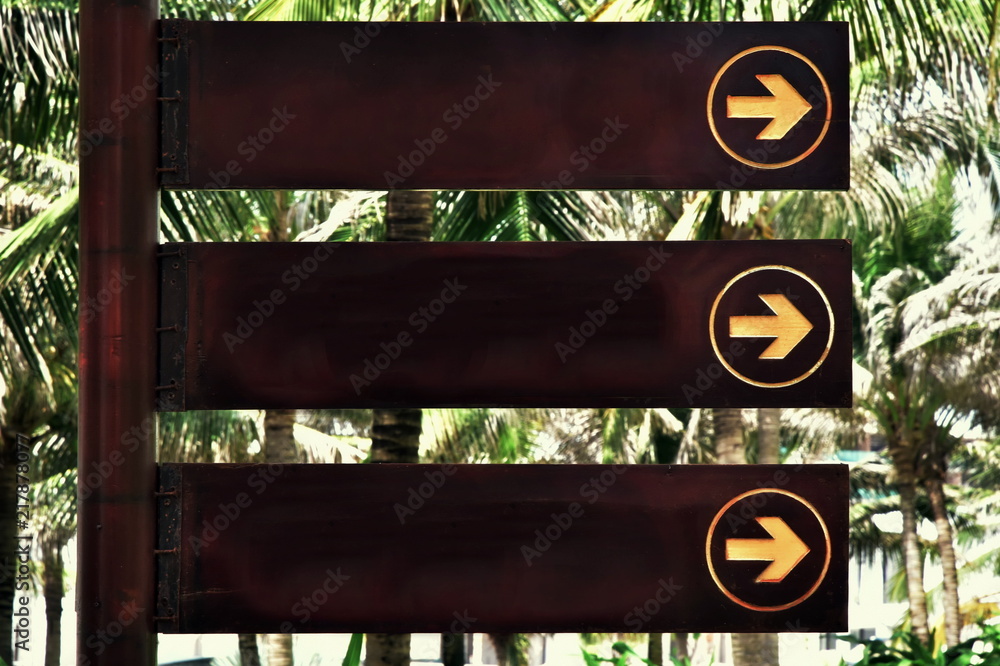 Wooden nameplate with index arrow and copy space. object on the background of palm trees