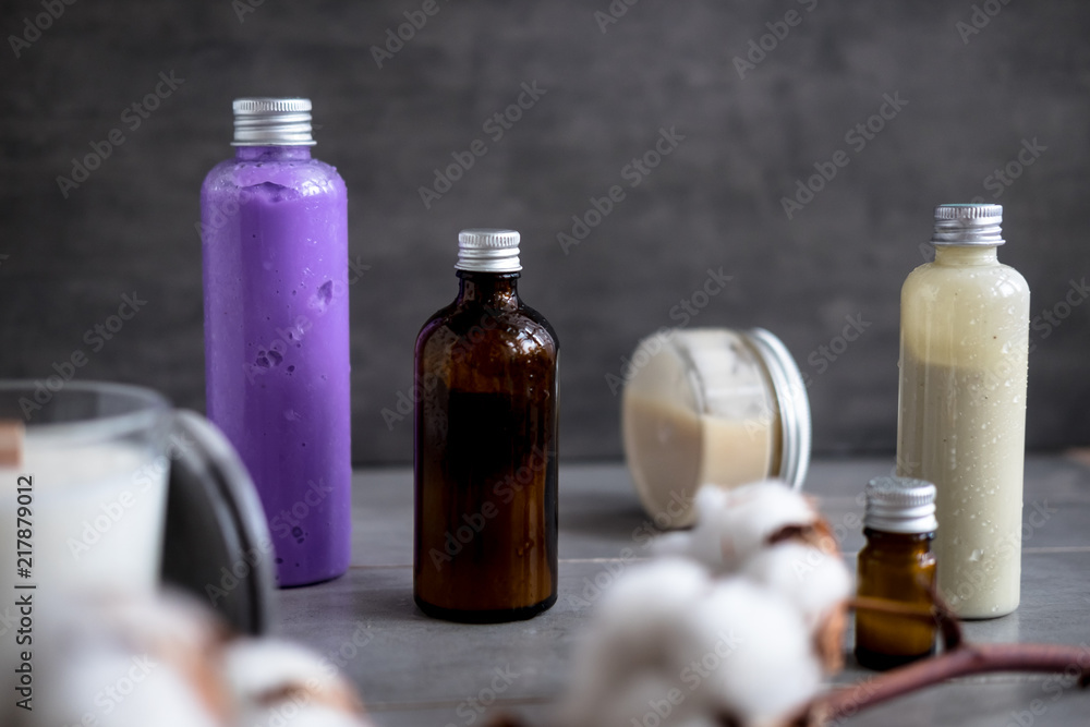 Bottles with natural spa cosmetic products on dark gray concrete table. Beauty blogger, salon treatments, minimalism concept Bottles with natural spa cosmetic products on dark gray concrete table. Beauty blogger, salon treatments, minimalism concept