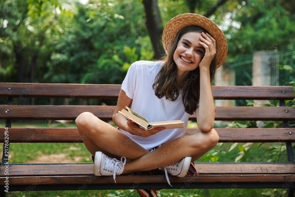 Cheerful young girl reading a book - obrazy, fototapety, plakaty 