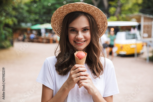 Happy young girl holding ice cream while standing